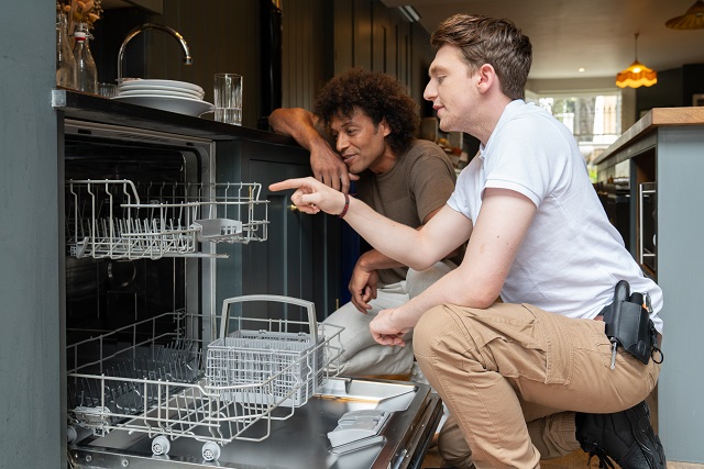Engineer fixing a dishwasher with a customer