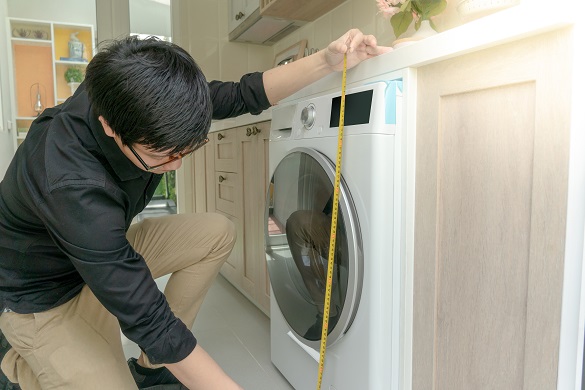 Asian man measuring a washing machine
