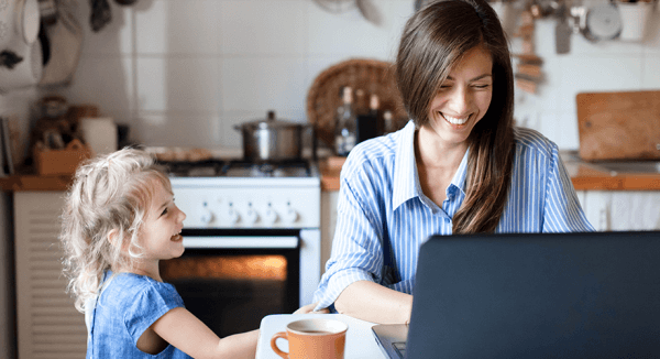 Caucasian mother and her young daughter laughing together in the kitchen